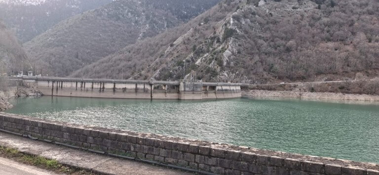 The historic Lake Plastira Dam during our winter minibus expedition. The impressive structure of the Lake Plastira Dam in Central Greece surrounded by mountain peaks.
